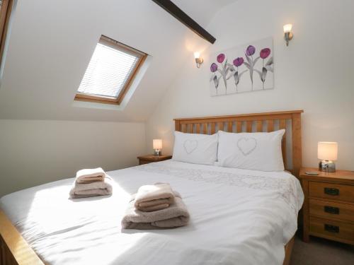 a bedroom with a white bed with towels on it at Burford Cottage in Weston on Avon
