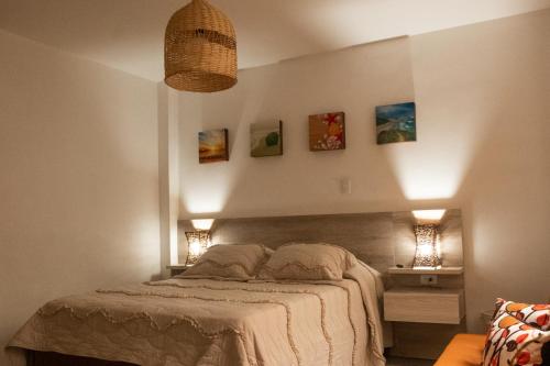 a bedroom with a bed with two lights on the wall at Hotel Casa Esencia in Medellín