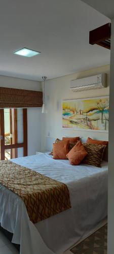 um quarto com uma grande cama branca com almofadas em Residencial Yacamim B39 em Ilhabela