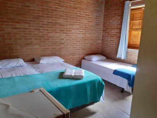 a room with two beds and a brick wall at Aconchego do Guara , próximo ao centro médico, Boldrini, Unicamp, Laboratório CNPEN, Universidades e Hospital Sobrapar in Barão de Geraldo