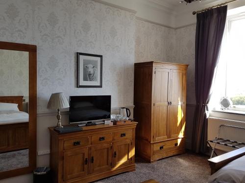 a bedroom with a tv on a wooden dresser and a bed at Herdwicks in Millom