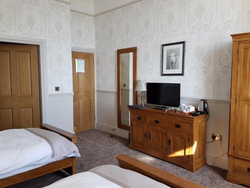 a bedroom with two beds and a television on a dresser at Herdwicks in Millom