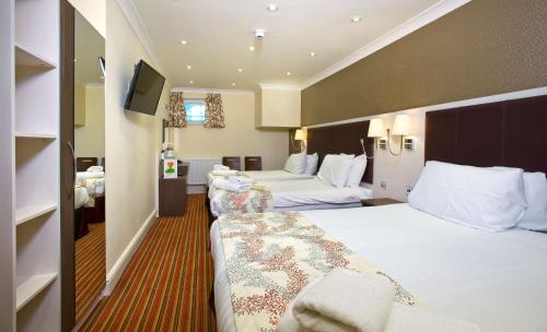 a hotel room with two beds and a flat screen tv at Best Western Chiswick Palace & Suites London in London