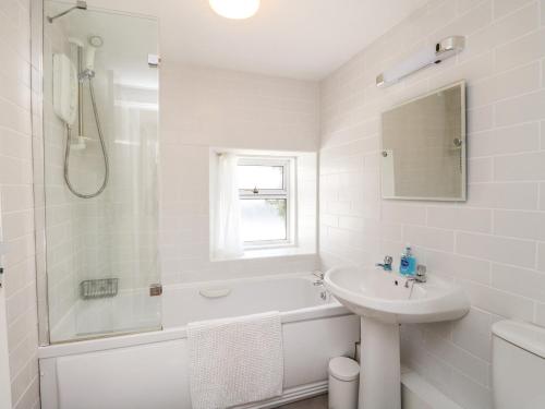 a white bathroom with a tub and a sink and a shower at The Knowe Lower in Taynuilt