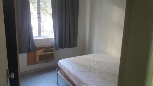 Habitación pequeña con cama y ventana en Apartamento Barata Ribeiro, en Río de Janeiro