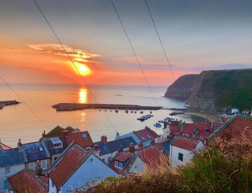 a view of a town with the sun setting over the ocean at The Anchorage your home in idyllic Staithes in Staithes