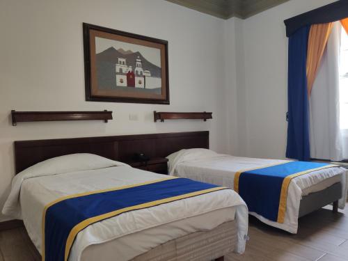 a bedroom with two beds and a picture on the wall at Hotel Sierra Gorda in Ciudad Victoria