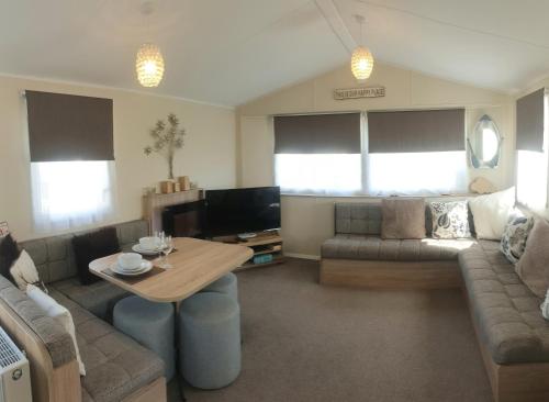 sala de estar con sofá y mesa en Griffiths, Seaview Caravan Park, Whitstable, en Kent