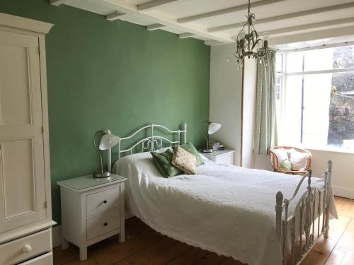 a bedroom with a bed with green walls and a window at The Anchorage your home in idyllic Staithes in Staithes