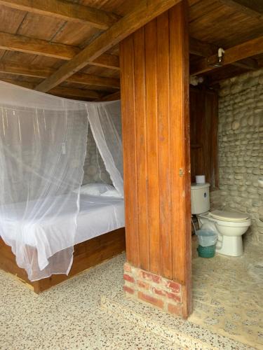 1 dormitorio con cama y aseo en EcoHostal Palmares Del Rio en Guachaca