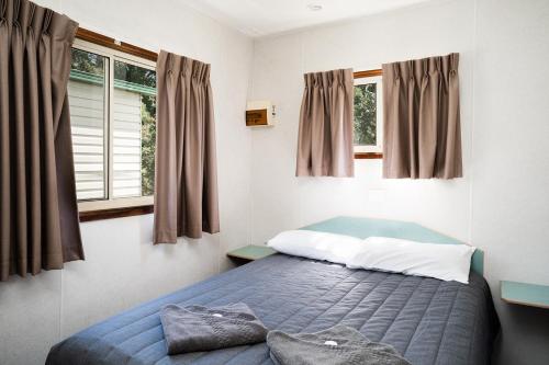 a bedroom with a bed and two windows at Gundagai Cabins & Tourist Park in Gundagai