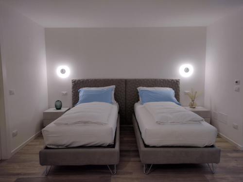 two twin beds in a room with two lamps at La Rondinella Apartments in Bardolino
