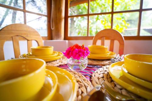 a table with yellow dishes and a vase of flowers at Bungalow Cajamarca, con Wifi y Cochera in Cajamarca