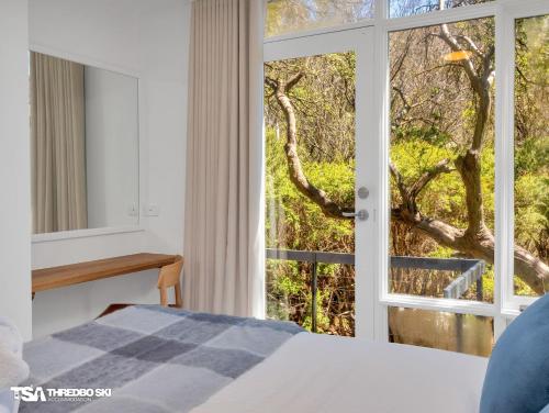 a bedroom with a bed and a large window at Stepping Stone in Thredbo