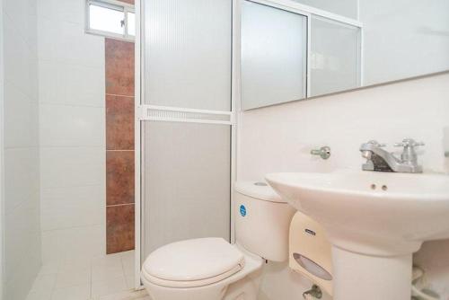 a white bathroom with a toilet and a sink at Hotel Rivera Del Mar in Barranquilla