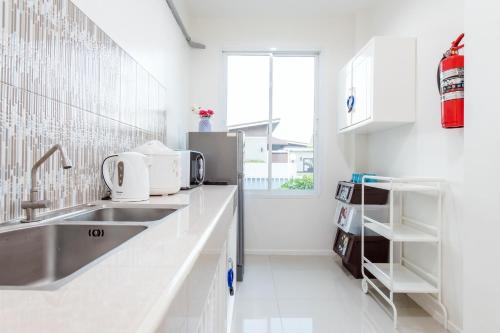 a white kitchen with a sink and a refrigerator at Mind Pool Villa Cha Am in Cha Am
