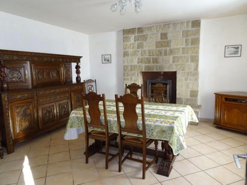 une salle à manger avec une table et une cheminée dans l'établissement Stone House in Treboul near Pointe du Raz, à Douarnenez