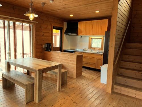 a kitchen with a wooden table and a wooden floor at Betsu Inn in Hakuba