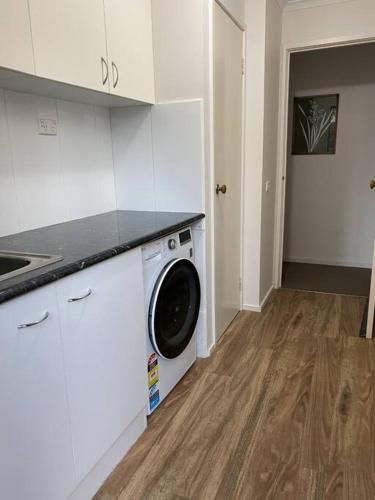 a kitchen with a washing machine in a white kitchen at Valley House - Location Location Location - Comfortable home in the heart of Healesville in Healesville
