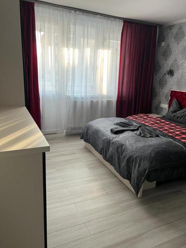 a bedroom with a bed and a window with red curtains at Apartament Adagio Felix in Baile Felix