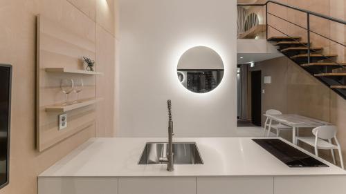 a kitchen with a sink and a staircase with a mirror at Albescent Poolvilla in Gyeongju