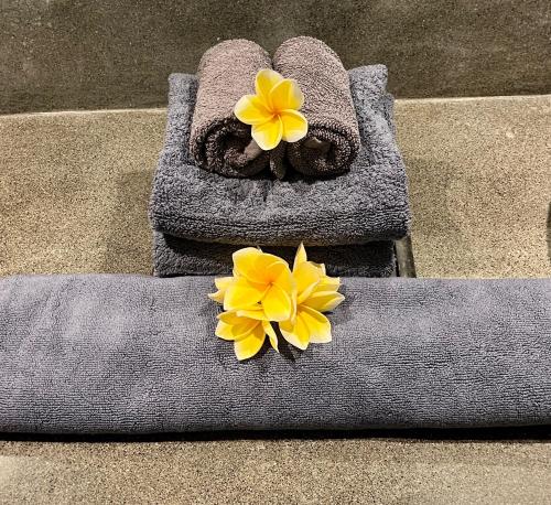 a towel with two yellow flowers on top of it at Pearl Boutique Hotel Adult only in Legian