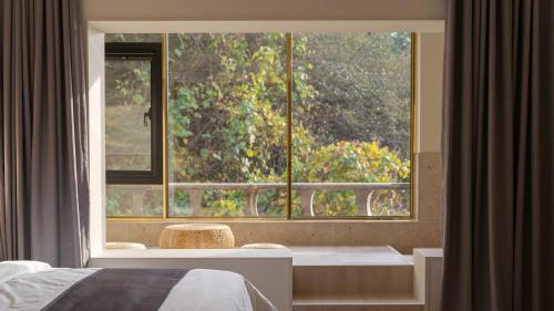 a bedroom with a large window in front of a bed at Denbasta forest Hotel in Busan