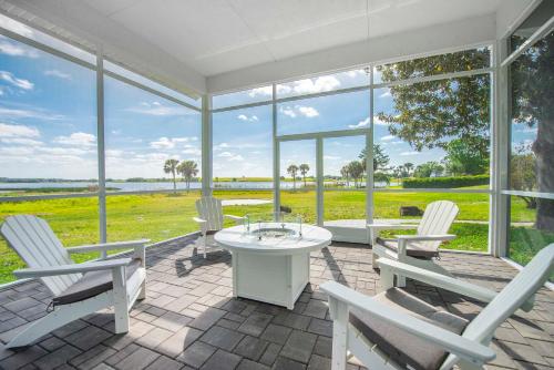 a patio with white chairs and a table and windows at Sumner Lake House 2B in Clermont
