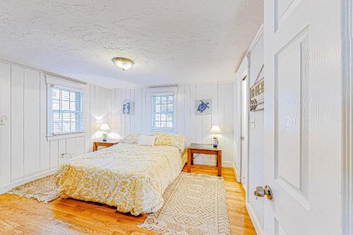 a white bedroom with a bed and two windows at Salty Kisses Main in Yarmouth