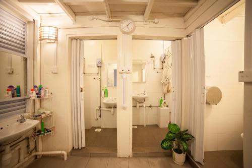 La salle de bains est pourvue d'un lavabo et d'une horloge murale. dans l'établissement Blanc Inn, à Singapour