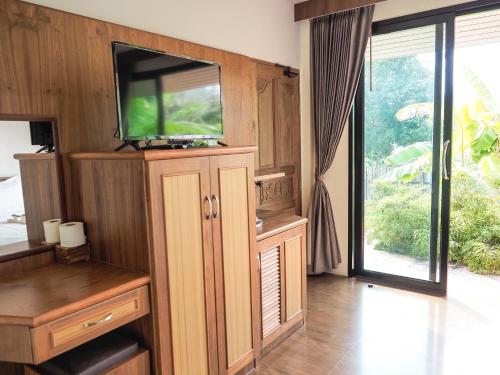 a living room with a flat screen tv on a cabinet at Bannsuan Amaleena in Ko Yao Noi