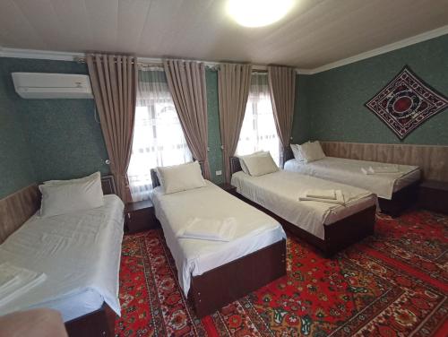 Cette chambre comprend 3 lits et un tapis. dans l'établissement OQSAROY SAMARKAND Guest House, à Samarcande