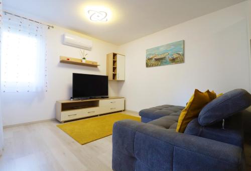 a living room with a blue couch and a flat screen tv at Galerius Golden Beach Apartment in Siófok