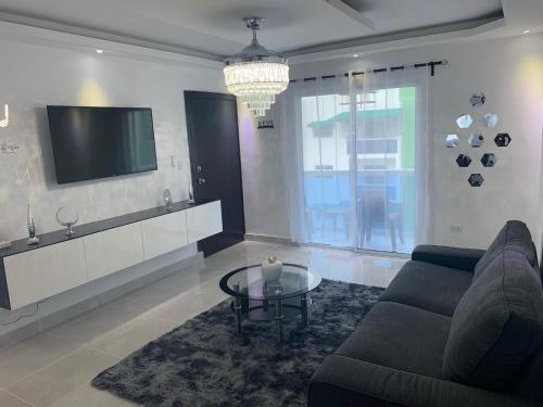 een woonkamer met een bank en een tv bij 3bed Apartment con Terraza y Picsina privada in Santo Domingo