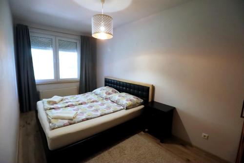 a small bedroom with a bed and a window at Galerius Golden Beach Apartment in Siófok