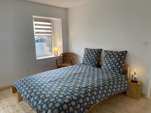 - une chambre avec un lit doté d'une couette bleue et d'une fenêtre dans l'établissement La Bulle du Quinze, à Mazaye