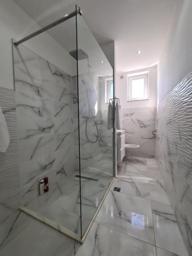 a glass shower in a bathroom with white marble at The Best Apartment in Hunedoara