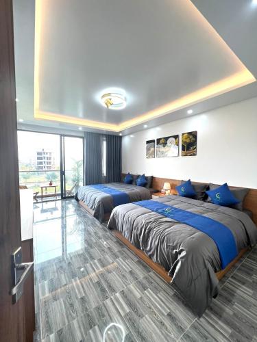 two beds in a hotel room with blue pillows at An Cường Hotel in Sầm Sơn