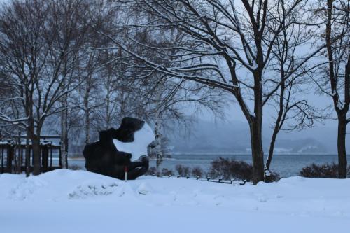 a statue of a person sitting in the snow at Guest house HiDE in Lake Toya