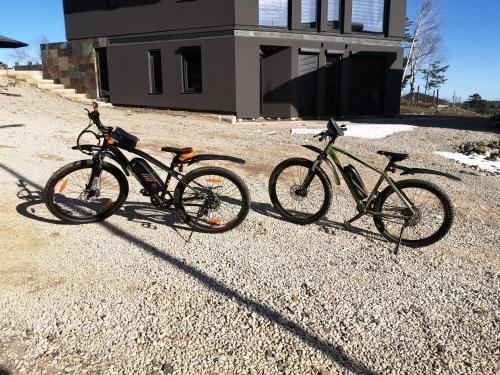 drie fietsen geparkeerd op het grind voor een gebouw bij Apartman Krnjajic Diamond Hill in Divčibare