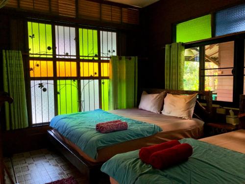 two beds in a room with green lights on the windows at Pop riverside trat in Trat