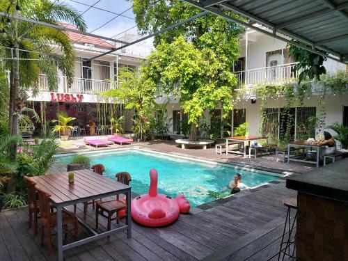 a pool with a table and a child in the water at Lushy Hostel Canggu in Canggu
