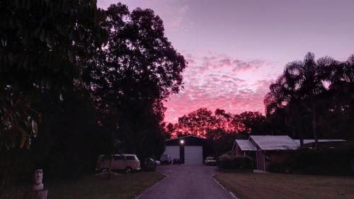 a sunset over a road with a house and trees at Tukawyl Retreat Landsborough in Landsborough