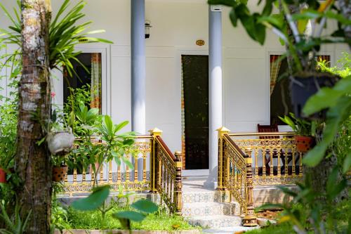 a house with a gold railing on the front porch at Kim Xuan Bungalow in Phu Quoc