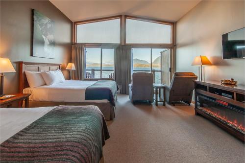 a hotel room with two beds and a large window at Himwitsa Lodge in Tofino