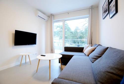 a living room with a couch and a table at Dwie Sosny z sauną, Sun & Snow in Ustronie Morskie