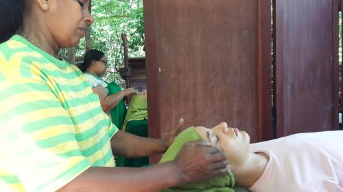 a woman sitting on a bed with her foot at Eco Village Yoga Home in Digana