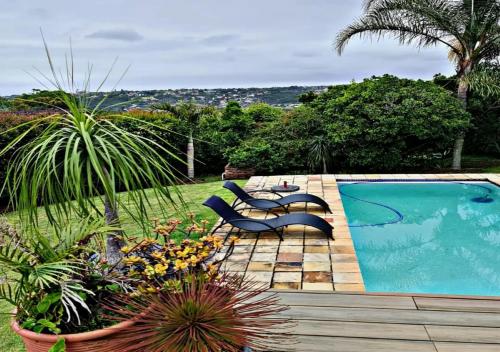 un patio trasero con una piscina con sillas y plantas en Summit Place, en East London