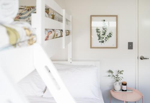 a white bedroom with a bed and a table at Villa Marlee Margaret River in Margaret River Town