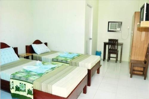 a room with three beds and a table and a chair at Villa Almedilla Pension House in Panglao